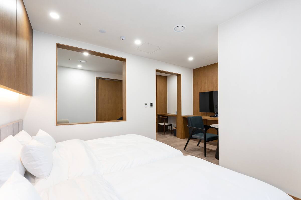 A modern hotel room with a large bed, a desk, and a television.
