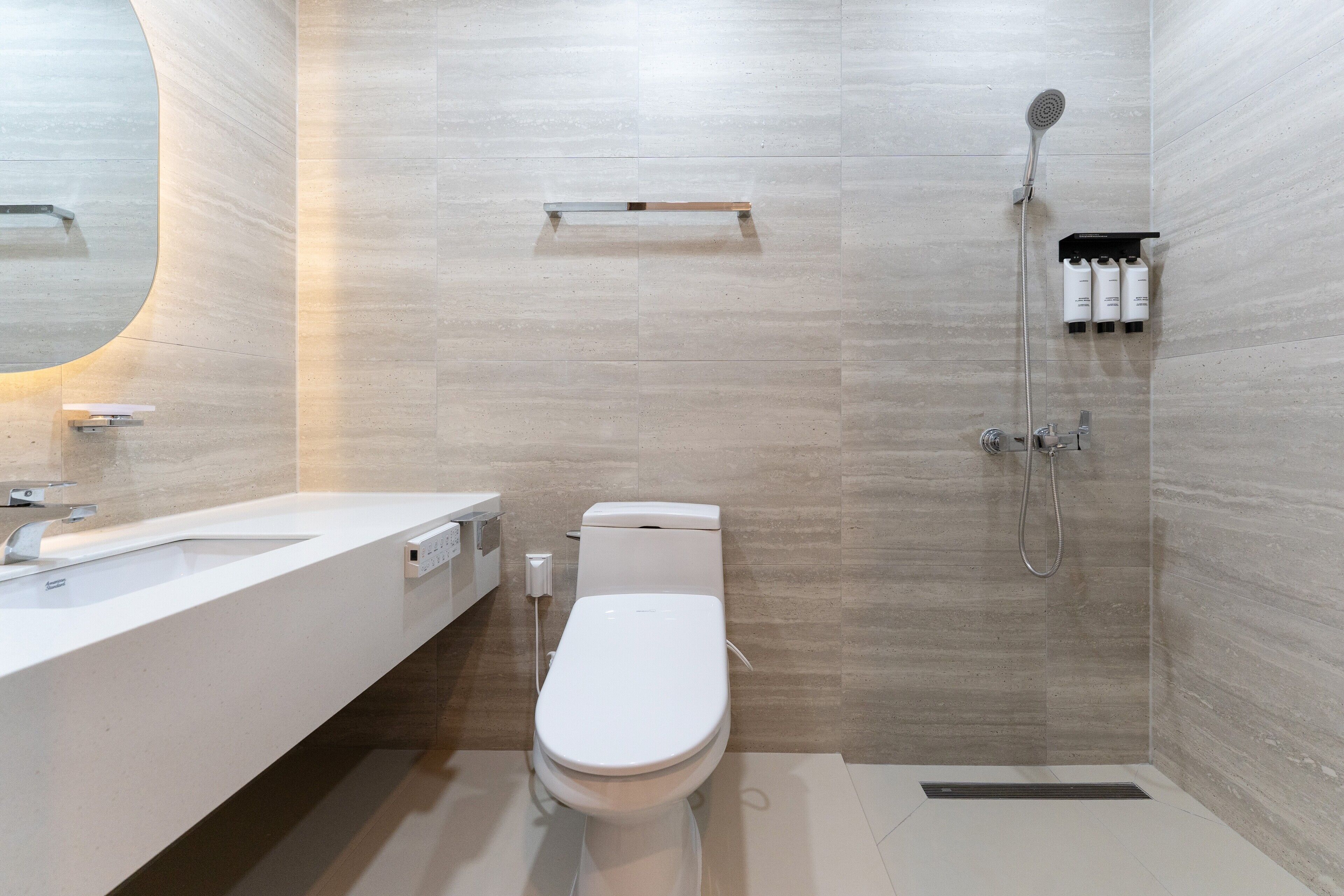 Et moderne badeværelse med hvid vask, toilet og brusebad.