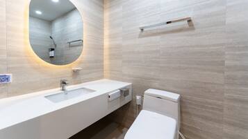 A modern bathroom with a large oval mirror, a white sink, and a toilet.
