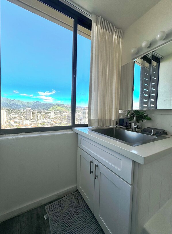 A modern kitchen with a large window, a sink, and cabinets.