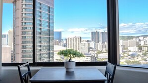 Blick aus einem Fenster mit einer Topfpflanze auf einem Tisch, mit Blick auf eine Skyline mit hohen Gebäuden.