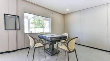 Un salón de conferencias con una mesa, sillas, un ventanal grande y un televisor instalado en la pared.