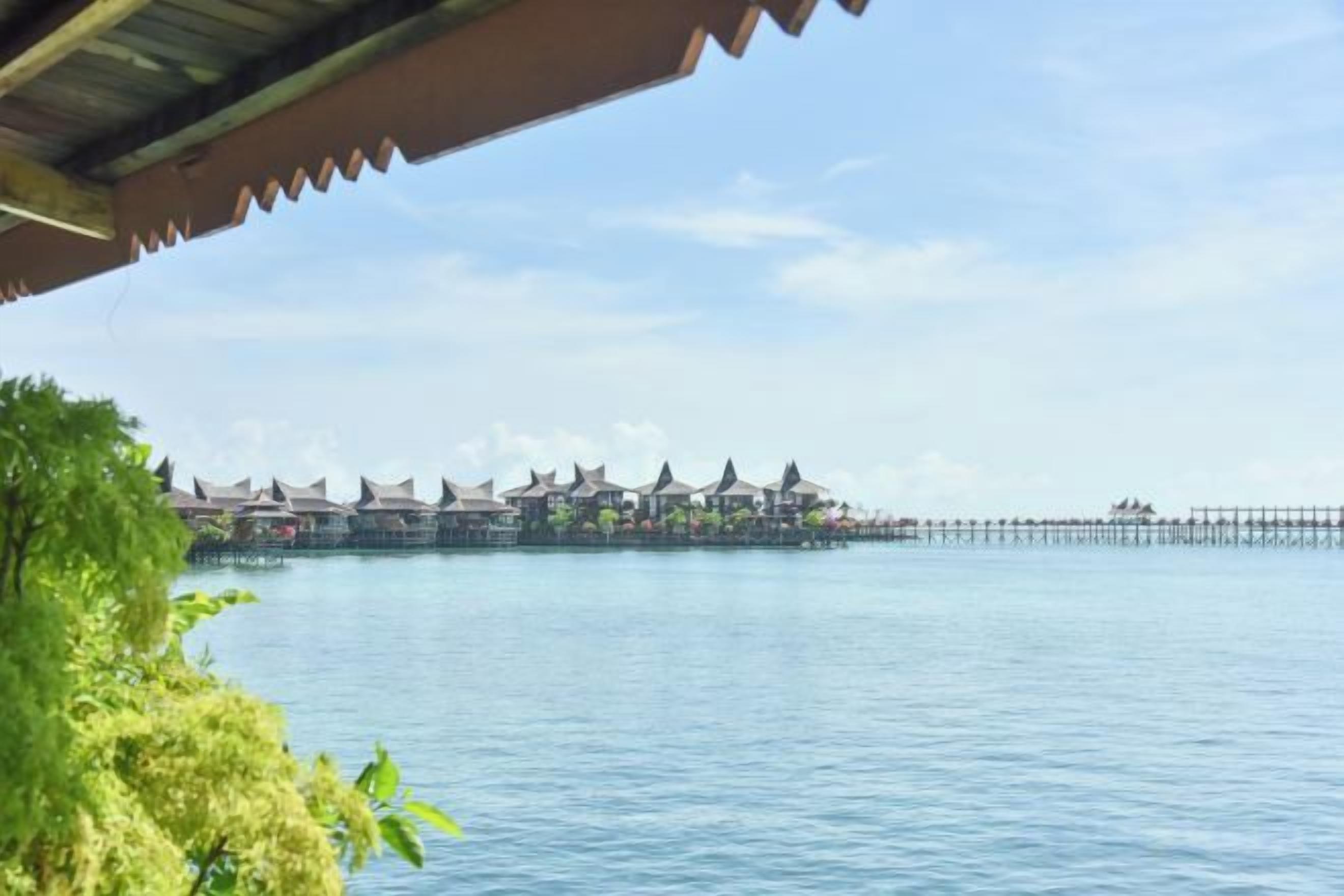 A waterfront view with a row of traditional-style buildings, a pier extending into the water, and a covered area with a roof.