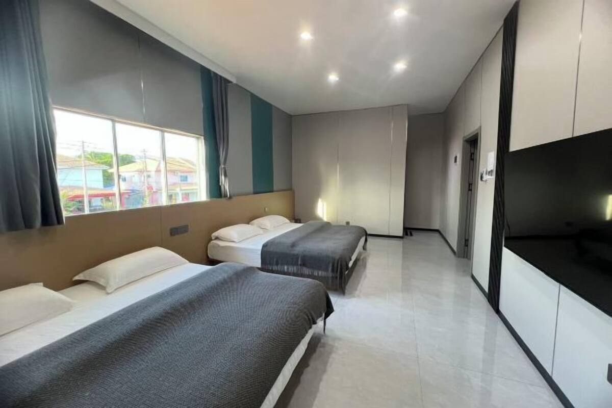 Une chambre d’hôtel avec deux lits, une télévision et une vue sur les maisons à travers la fenêtre.