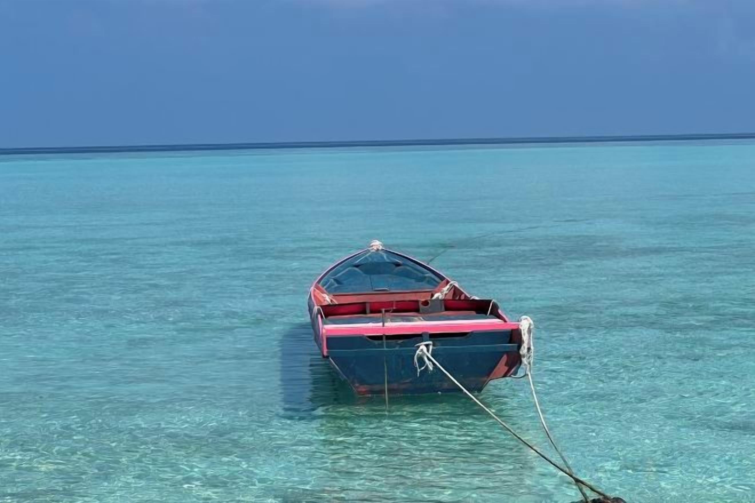A small boat anchored in clear turquoise water.