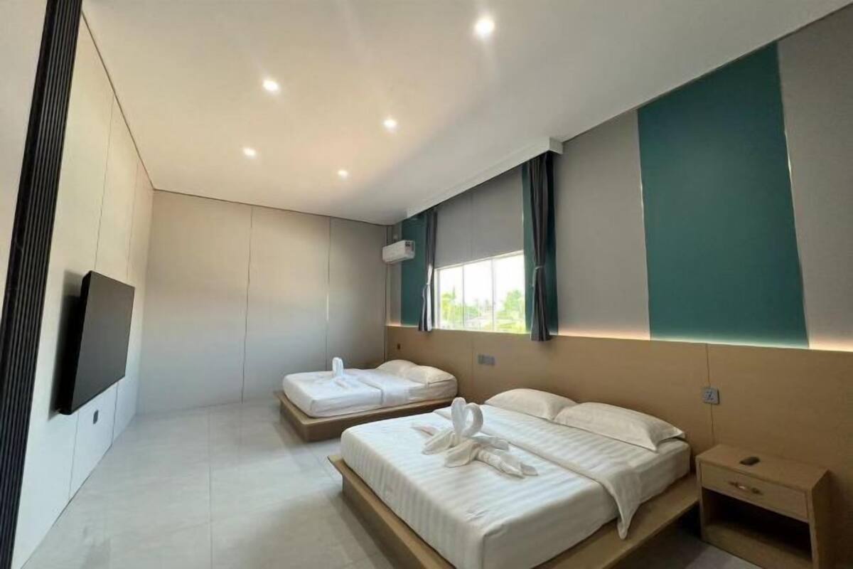 Une chambre d’hôtel moderne avec deux lits, un téléviseur à écran plat et une fenêtre avec des rideaux.