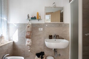 Een badkamer met een wit wastafel, een spiegel, een handdoekhouder en een douchegedeelte.