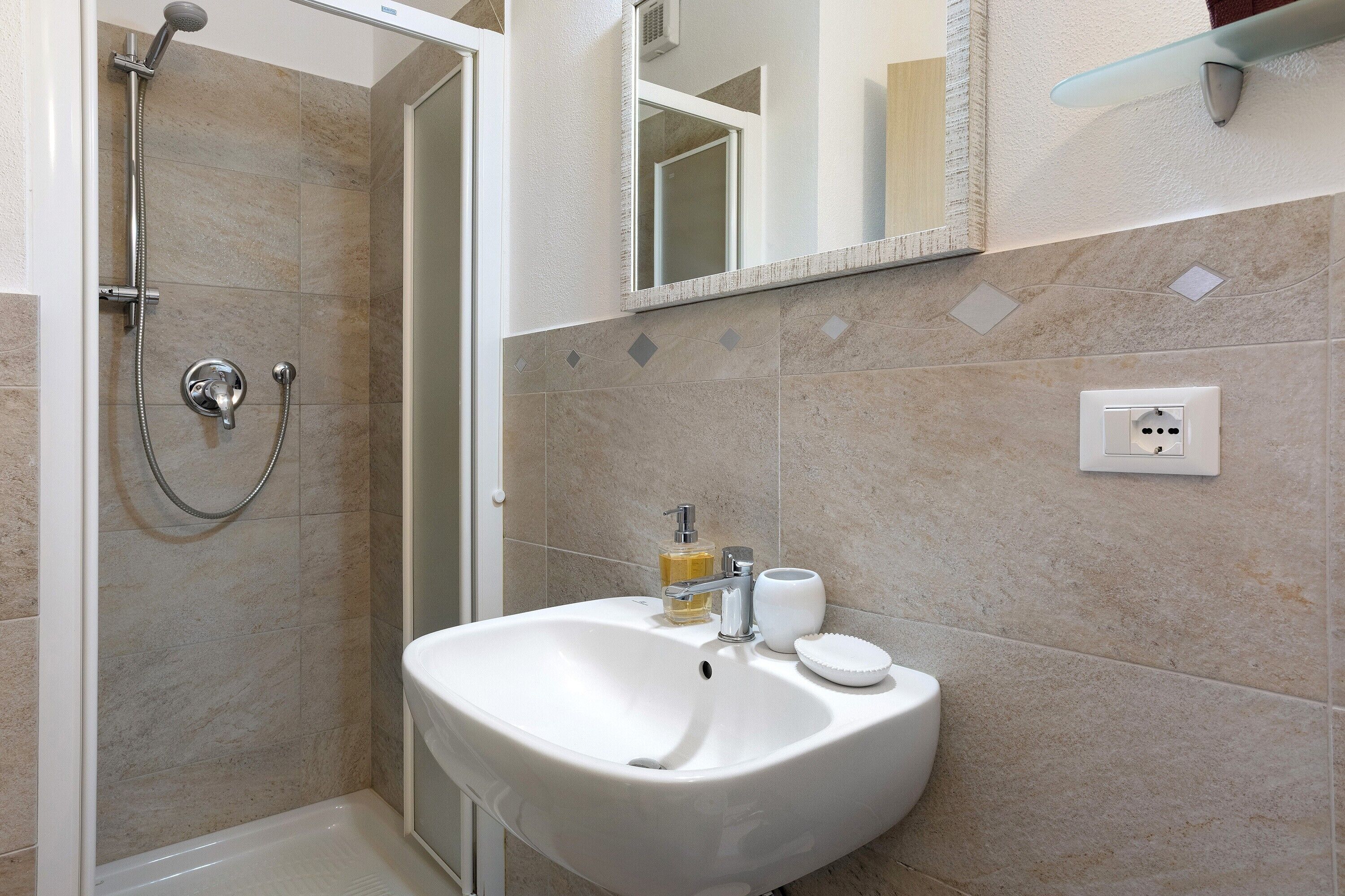 A bathroom with a shower, sink, and mirror.