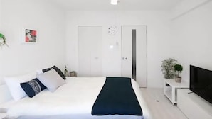 Una habitación de hotel moderna con una cama, un televisor, una planta y una puerta.