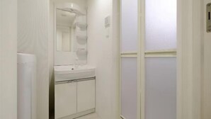 Un pasillo estrecho con una puerta, un radiador y un lavabo blancos, además de un espejo sobre el lavabo.