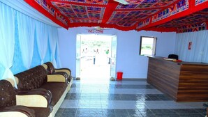 A reception area with a reception desk, a waiting area with sofas, and a tiled floor. - Jodhani Desert Camp & Resort Jaisalmer (Jaisalmer)