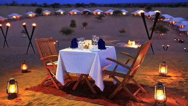 A desert dining setup with a table, chairs, and lanterns. - Jodhani Desert Camp & Resort Jaisalmer (Jaisalmer)