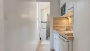 A narrow hallway leading to a kitchen with white cabinets, a wooden countertop, and a sink. - Charming studio, train station nearby (Tours)