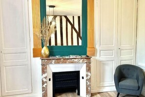 A room with a fireplace, a chair, and a mirror above it. - Charming studio, train station nearby (Tours)