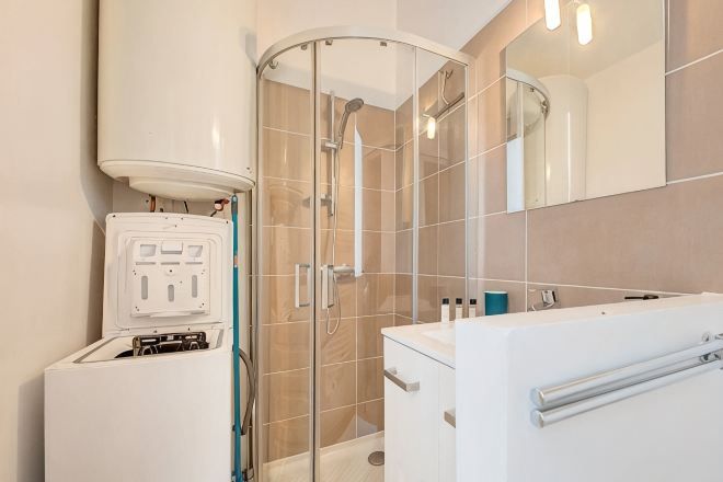 Une salle de bain moderne avec une douche à l’italienne en verre, un lavabo blanc et un miroir.