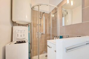 A modern bathroom with a glass shower enclosure, a white sink, and a mirror. - Charming studio, train station nearby (Tours)