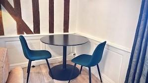 A corner room with a round table and two chairs, wooden beams on the wall, and a blue curtain. - Charming studio, train station nearby (Tours)