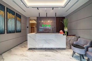 A hotel reception area with a marble reception desk, a seating area with a grey sofa, and framed artwork on the walls. - B&M HOTEL (Ho Chi Minh City)