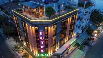 Un hotel con un llamativo letrero que dice 'HOTEL', una terraza en la azotea y una fachada bien iluminada.