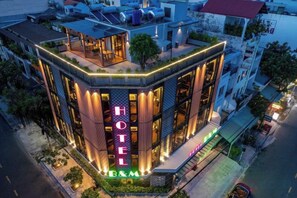 A hotel with a prominent 'HOTEL' sign, a rooftop terrace, and a well-lit facade. - B&M HOTEL (Ho Chi Minh City)