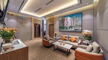 A modern hotel lobby with a reception desk, seating area, and a large painting on the wall.