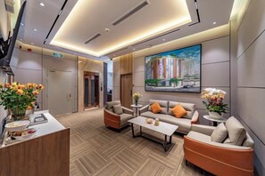 Eine moderne Hotelhalle mit Empfangsschalter, einer Sitzecke und einem großen Gemälde an der Wand.