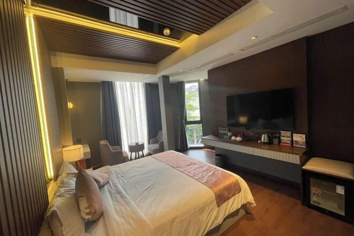 Una habitación de hotel con cama, escritorio, televisor y zona de estar.