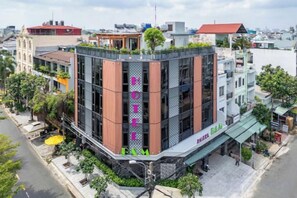 Un hôtel à plusieurs étages au design moderne, doté de balcons et d’un jardin sur le toit.
