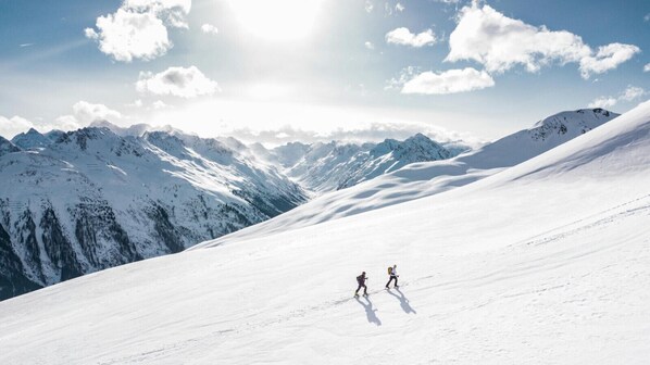 A snowy mountain landscape with two skiers.