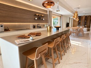 A modern kitchen with a central island, bar stools, and a dining area with a table and chairs.