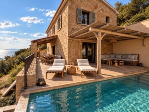 A stone house with a pool, outdoor seating, and a view of the sea. - Villa Lunassina (Cargèse)