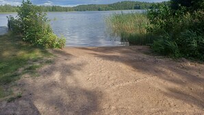 A gravel path leading to a lake with dense vegetation on both sides. - Cottage Baydar (Kouvola)