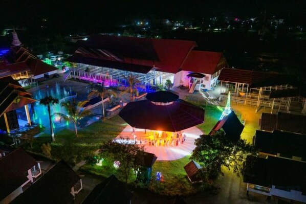 A hotel with a swimming pool, a covered outdoor area, and multiple buildings with red roofs.