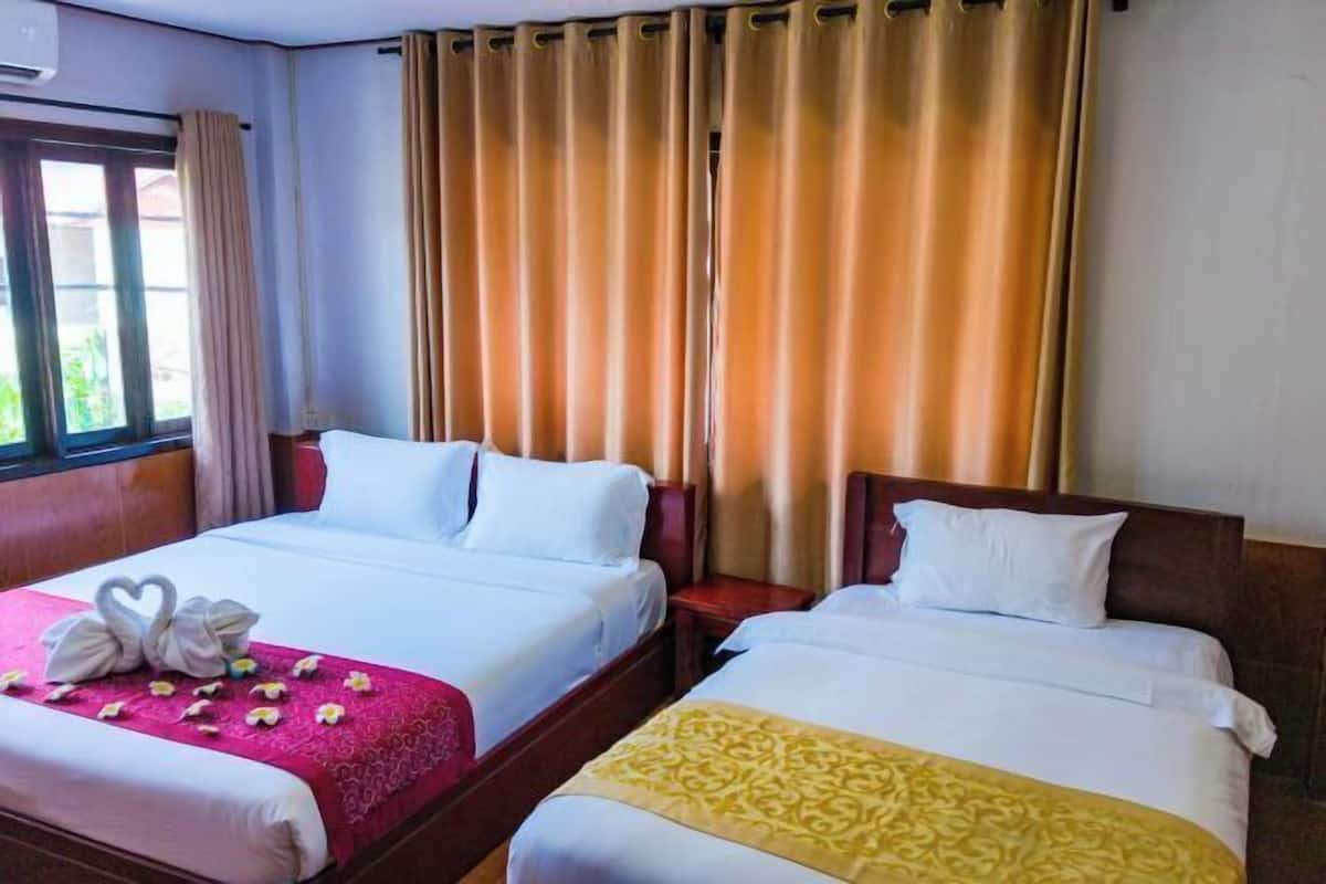 Quarto de hotel com duas camas, uma janela com cortinas e um ar condicionado fixado na parede.