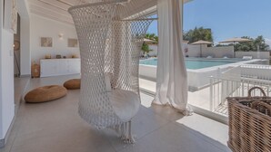 A room with a hanging chair, a pool, and a view of the outdoors.