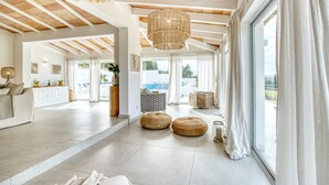 A spacious hotel lobby with a high ceiling, a large window offering a view of the outdoors, and a modern chandelier.