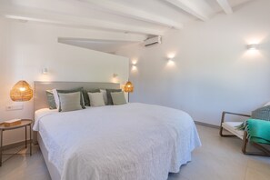 Un dormitorio con una cama grande, mesitas de noche, una silla y lámparas de pared.