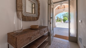 A wooden vanity with a mirror, a clear vase, and a woven basket.