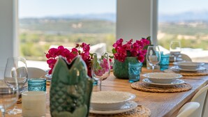 A dining table set with plates, glasses, and decorative vases, overlooking a scenic landscape.