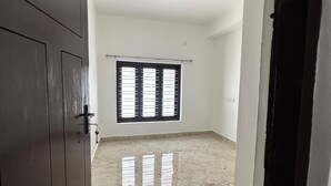 Ein Zimmer mit Marmorboden, einem großen Fenster mit Jalousien und einer dunklen Holztür.