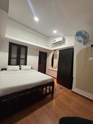 Une chambre à coucher comprenant un lit, une armoire, un miroir et un appareil de climatisation.