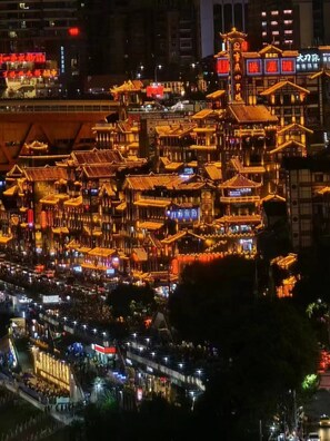 A traditional Chinese architectural complex with multiple buildings, illuminated signs, and a crowd of people. - Chongqing Justom Family Apartment Hotel (Chongqing)