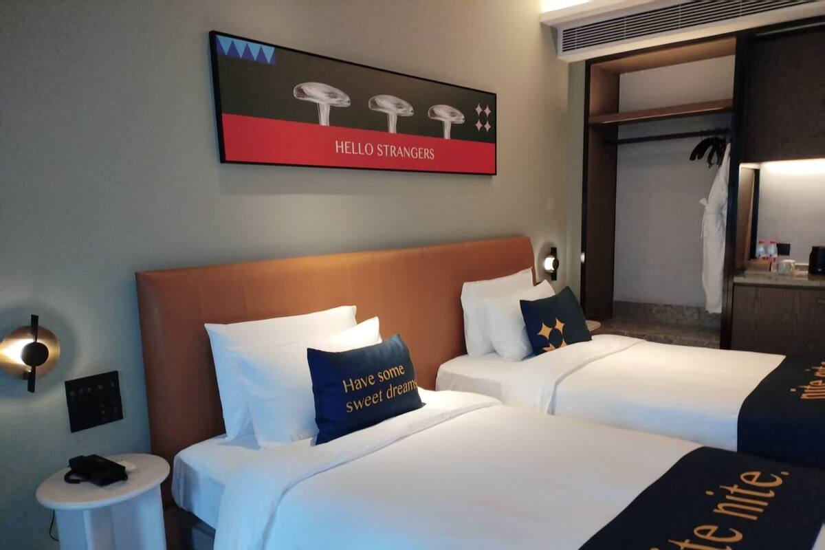 Ein Hotelzimmer mit zwei Betten, einer Nachttischlampe und einem Wandbild.