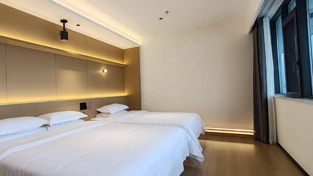 A modern hotel room with a large bed, bedside tables, and a large window with curtains. - Chongqing Justom Family Apartment Hotel (Chongqing)