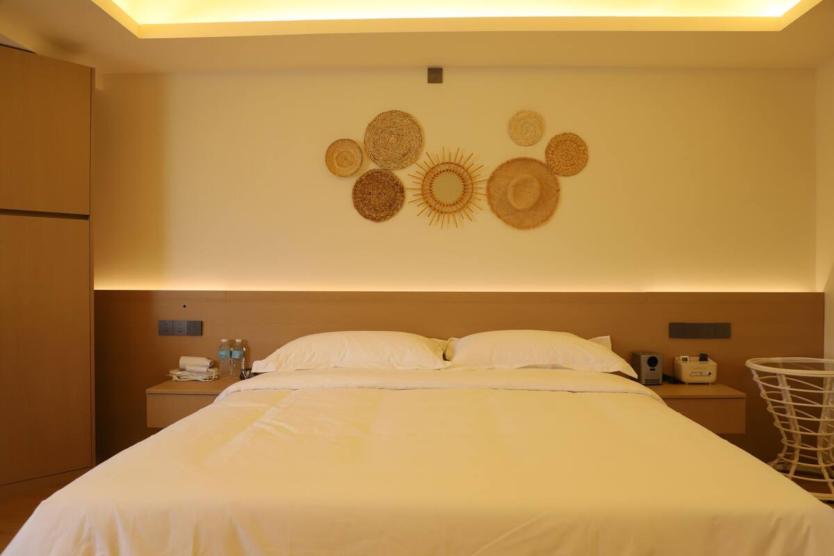 Ein Hotelzimmer mit einem großen Bett, einem Nachttisch mit Telefon und Lampe sowie einer Wand mit Wandbehängen.
