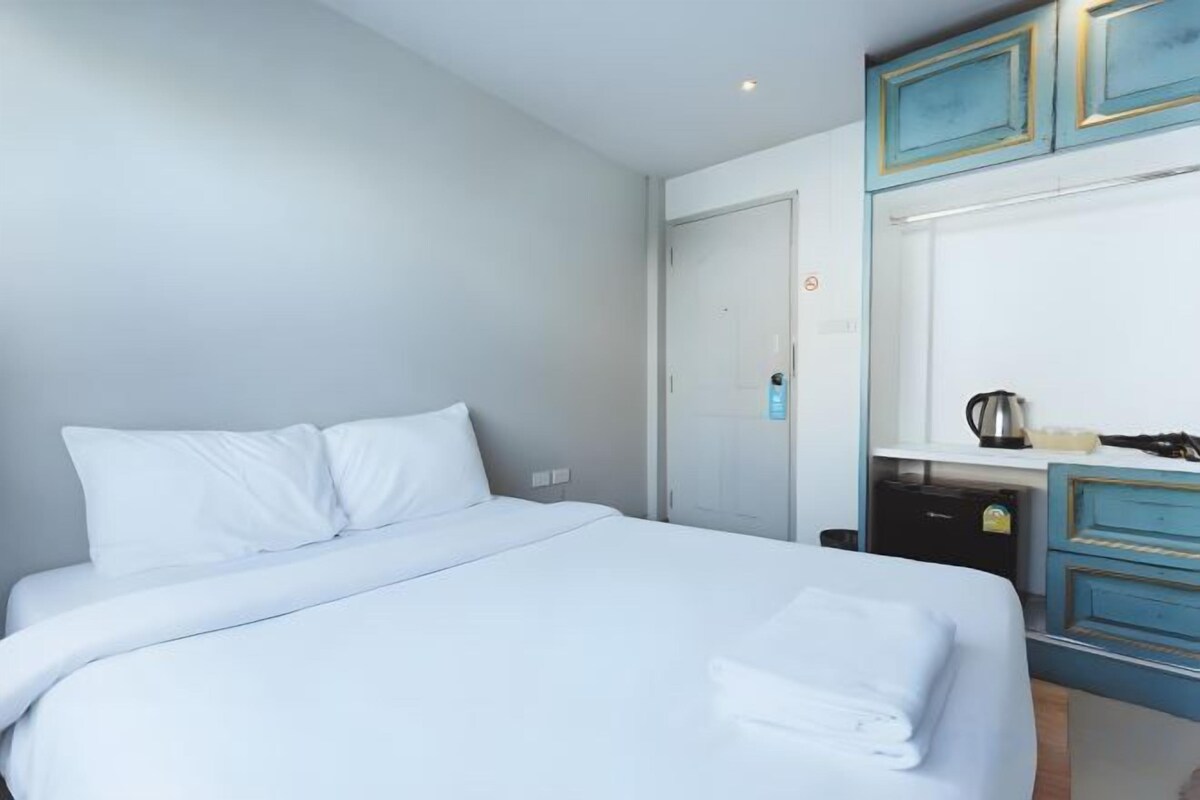 A hotel room with a bed, a desk, and a door.