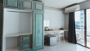 A modern hotel room with a kitchenette, a desk, a chair, and a large window with a view. - Mitr Inn Nimman (Chiang Mai)