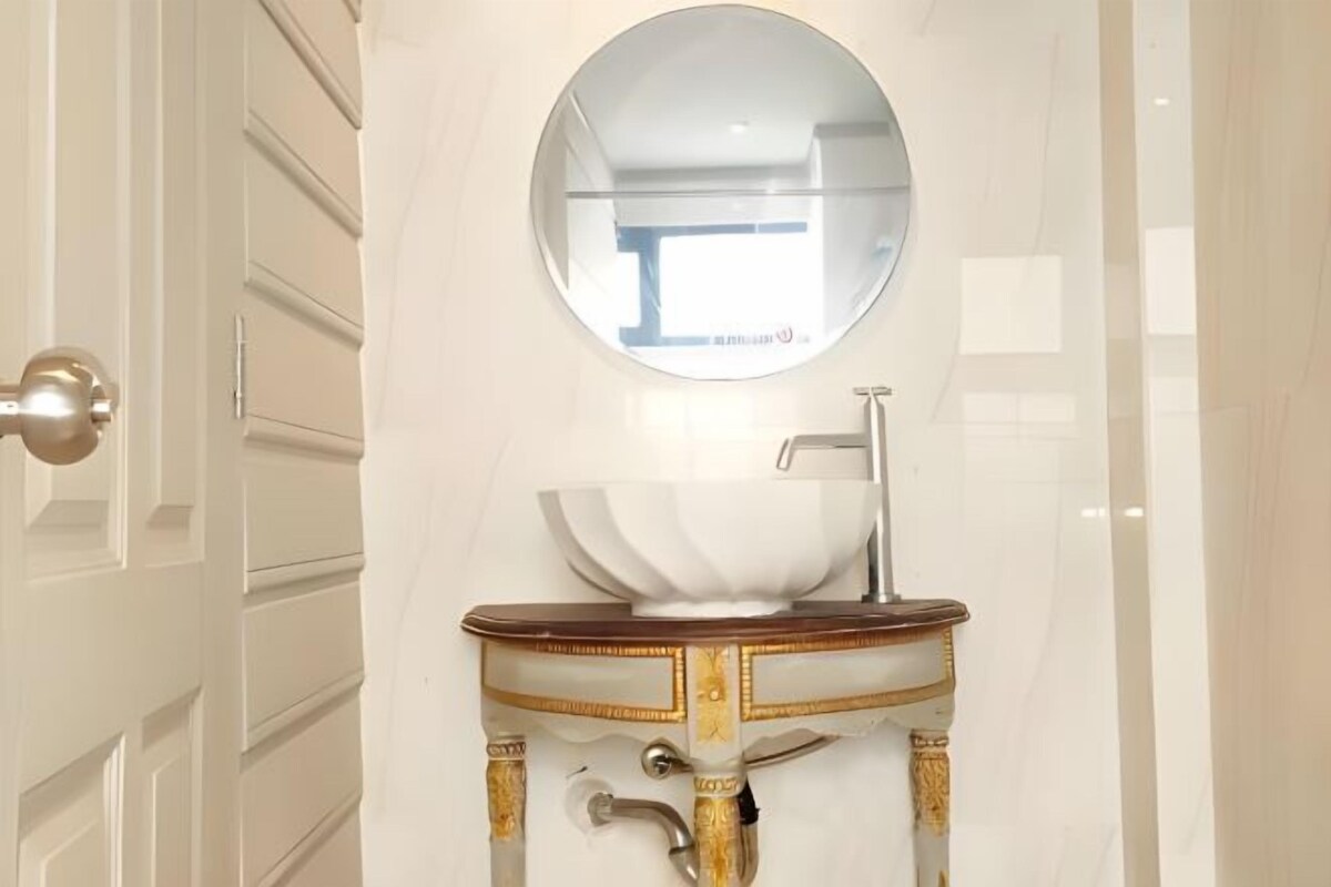A bathroom with a white vanity, a round mirror, and a sink.