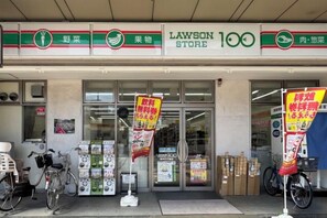 A Lawson store entrance with promotional signs, bicycles, and a clear glass facade. - Tokyo Sakura Hotel (Tokyo)