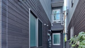 A narrow corridor with a dark wooden exterior, a small balcony, and a security camera. - Tokyo Sakura Hotel (Tokyo)
